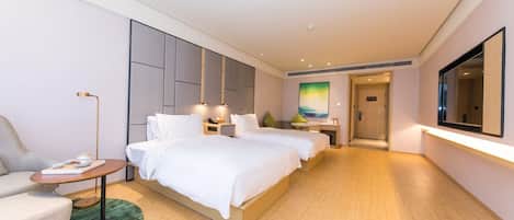 A hotel room with a bed, bedside tables, a desk, a chair, and a large mirror.
