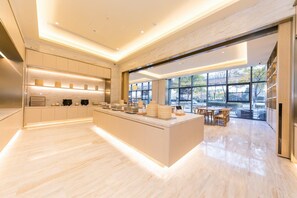 A modern kitchen with a central island, built-in appliances, and a dining area with natural light. - Ji Hotel Wuxi East Station (Wuxi)