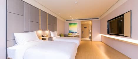 A hotel room with two beds, a TV mounted on the wall, and a wooden floor.
