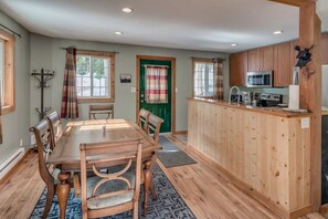 Una cocina acogedora con armarios de madera, una isla central y un comedor con mesa y sillas.