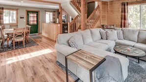 A spacious living room with a large sectional sofa, a wooden coffee table, and a staircase leading to an upper level.