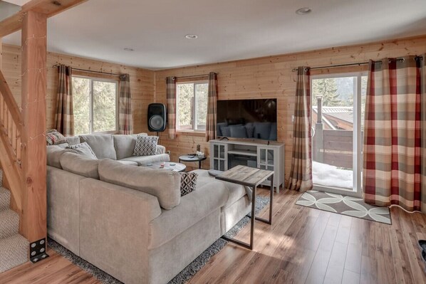 A cozy living room with a sectional sofa, a TV, and a wooden interior.