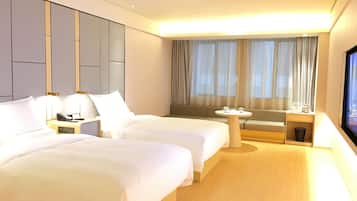 A hotel room with two beds, a small table, a sofa, and a TV.