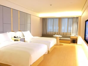 Habitación de hotel con dos camas, una mesita, un sofá y un televisor.