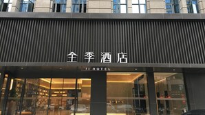 Entrada de hotel con diseño moderno, destacada por un letrero llamativo y fachada de vidrio.