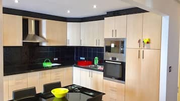 Een moderne keuken met een centraal kookeiland, inbouwapparatuur en een zwart aanrecht.
