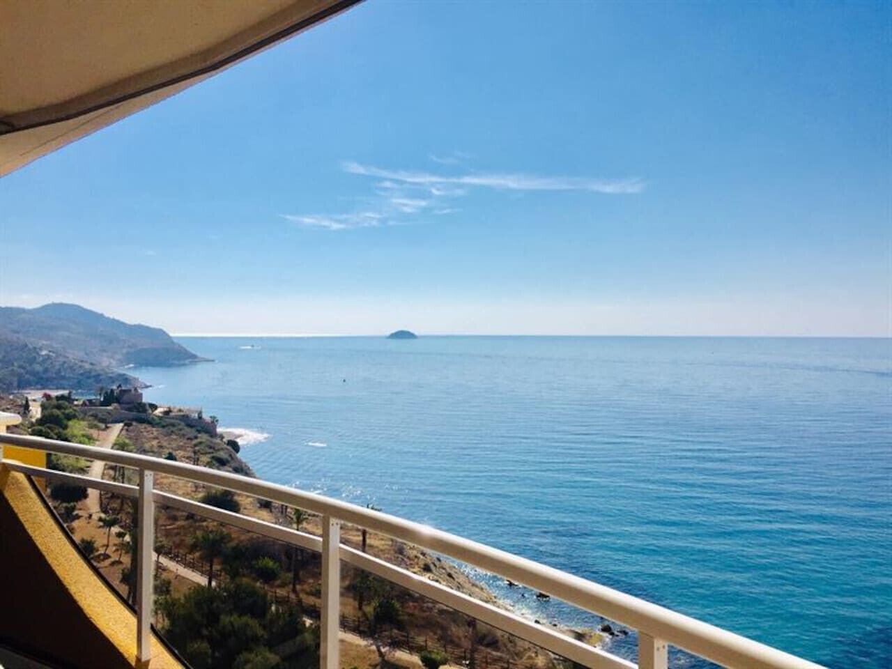 Blick aufs Meer und eine entfernte Insel vom Balkon aus, mit Geländer.