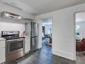 A modern kitchen with stainless steel appliances, a built-in oven, and a refrigerator. - Romantic Garden Apartment on Chatham Square (Savannah)