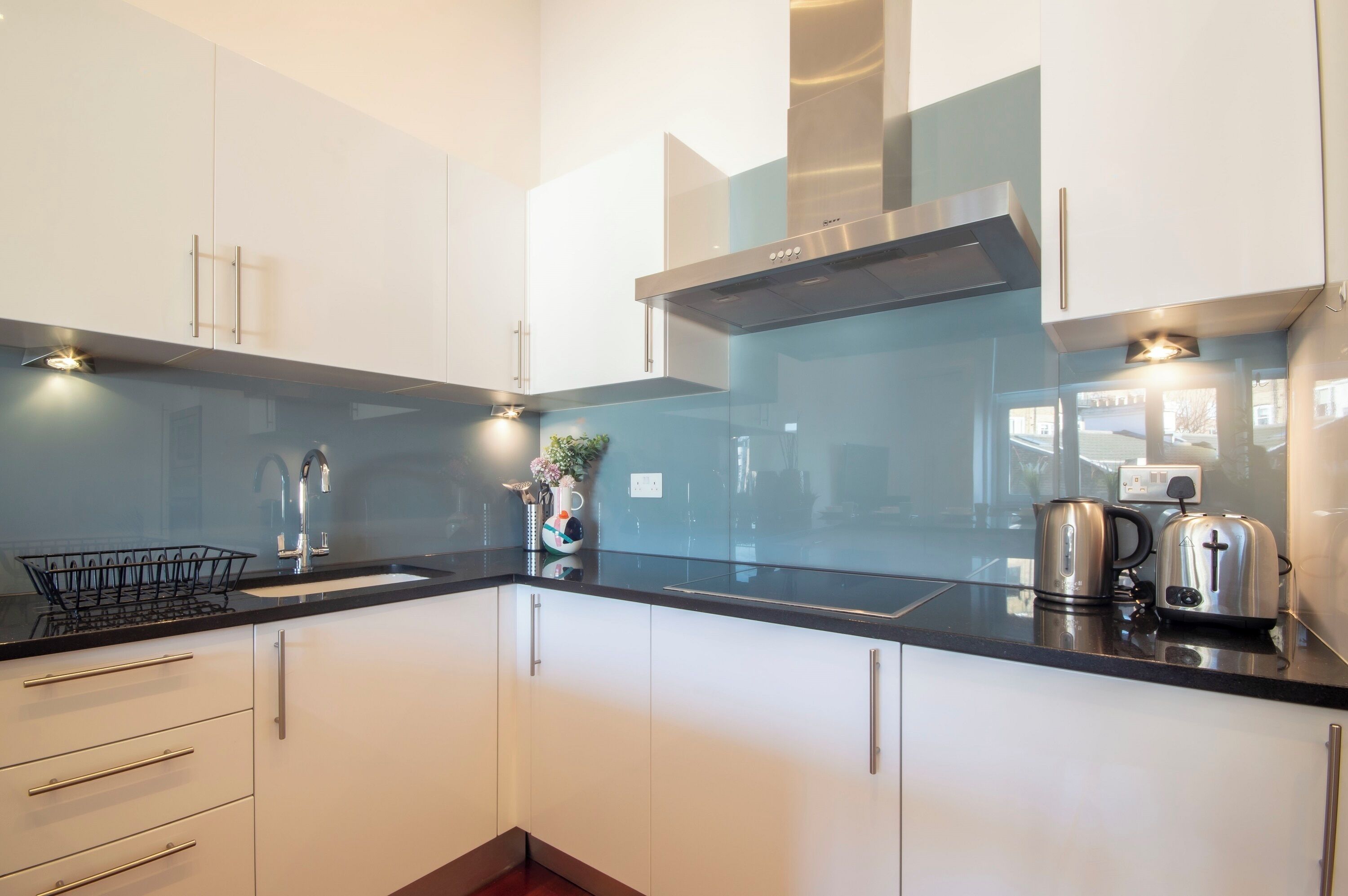 A modern kitchen with white cabinets, a black countertop, stainless steel appliances, and a visible electrical outlet.