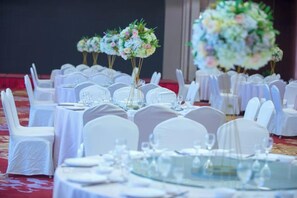 A banquet hall with round tables set for dining, white chairs, and floral centerpieces. - Lanxin Hotel (Shaoxing)