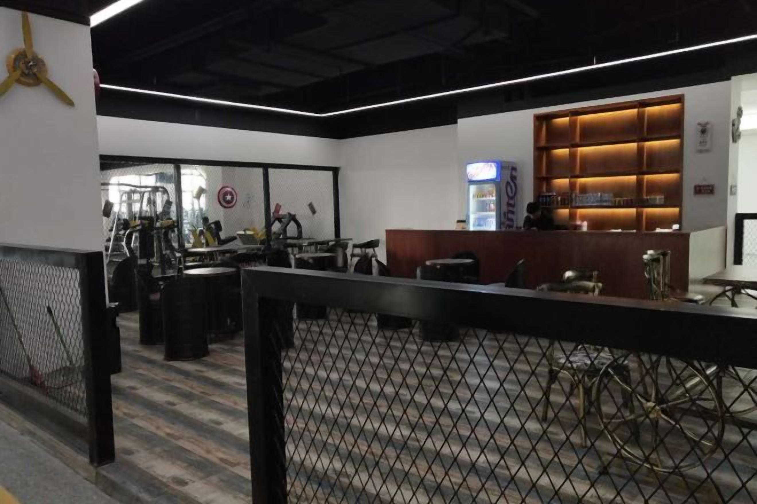 Una palestra con attrezzature per esercizi, una reception e un televisore a parete.