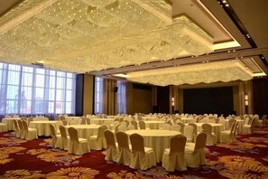A banquet hall with round tables and chairs, large windows, and a decorative ceiling. - Lanxin Hotel (Shaoxing)