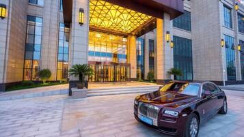 A luxury building with a grand entrance, a parked luxury car, and a well-maintained exterior.