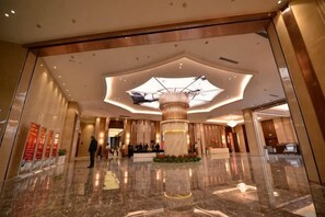 A spacious lobby with a high ceiling, a central column, and a reflective floor. - Lanxin Hotel (Shaoxing)