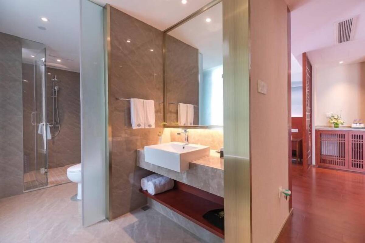 A modern bathroom with a glass shower enclosure, a white sink, and a mirror above it.