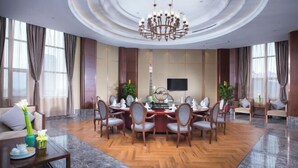 A spacious dining area with a round table, multiple chairs, and a chandelier. - Lanxin Hotel (Shaoxing)