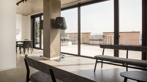 En modern inredning med ett matområde, stora fönster och utsikt över stadsbilden.
