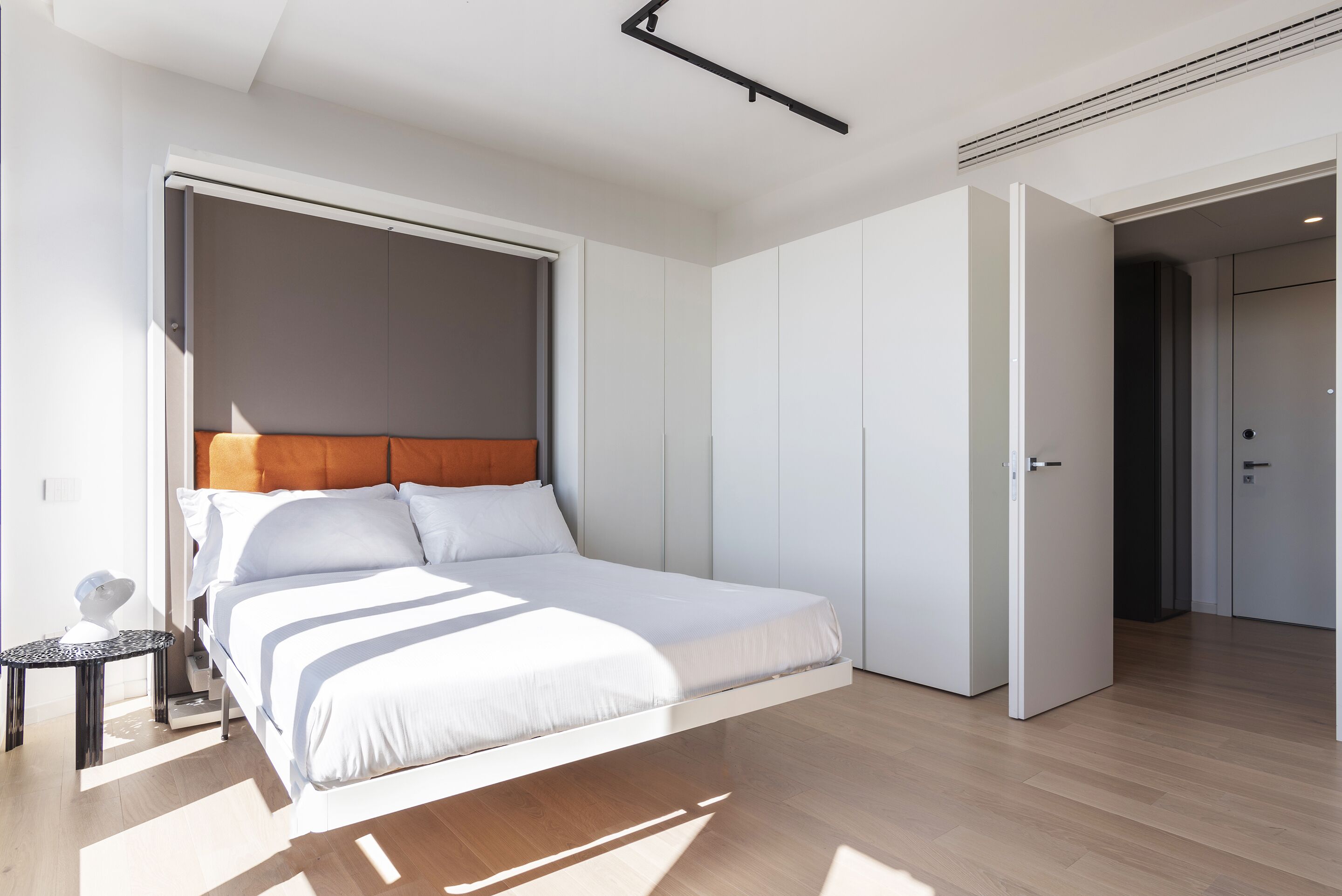 Un dormitorio moderno con cama, mesita de noche y armario.
