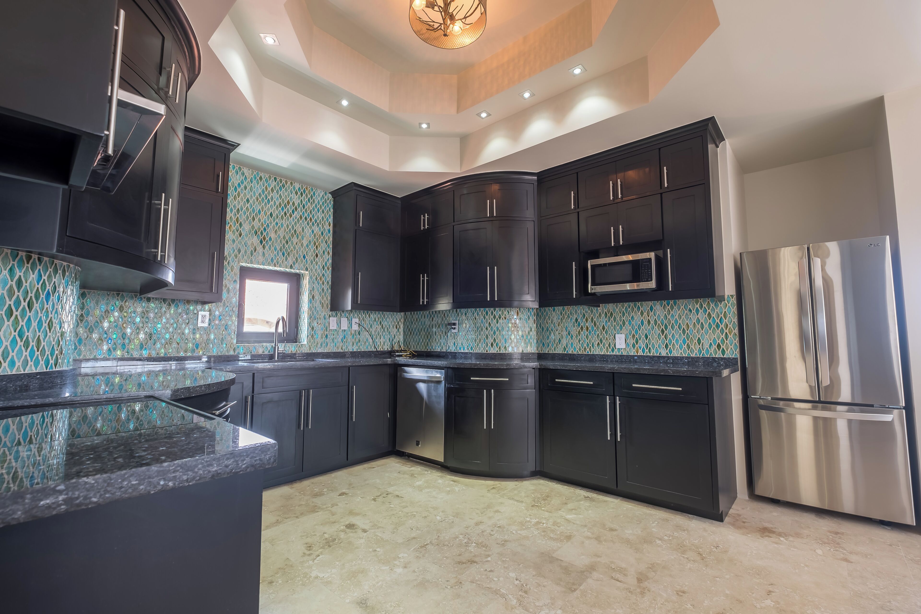 Una cocina moderna con gabinetes oscuros, electrodomésticos de acero inoxidable y un salpicadero de azulejos.