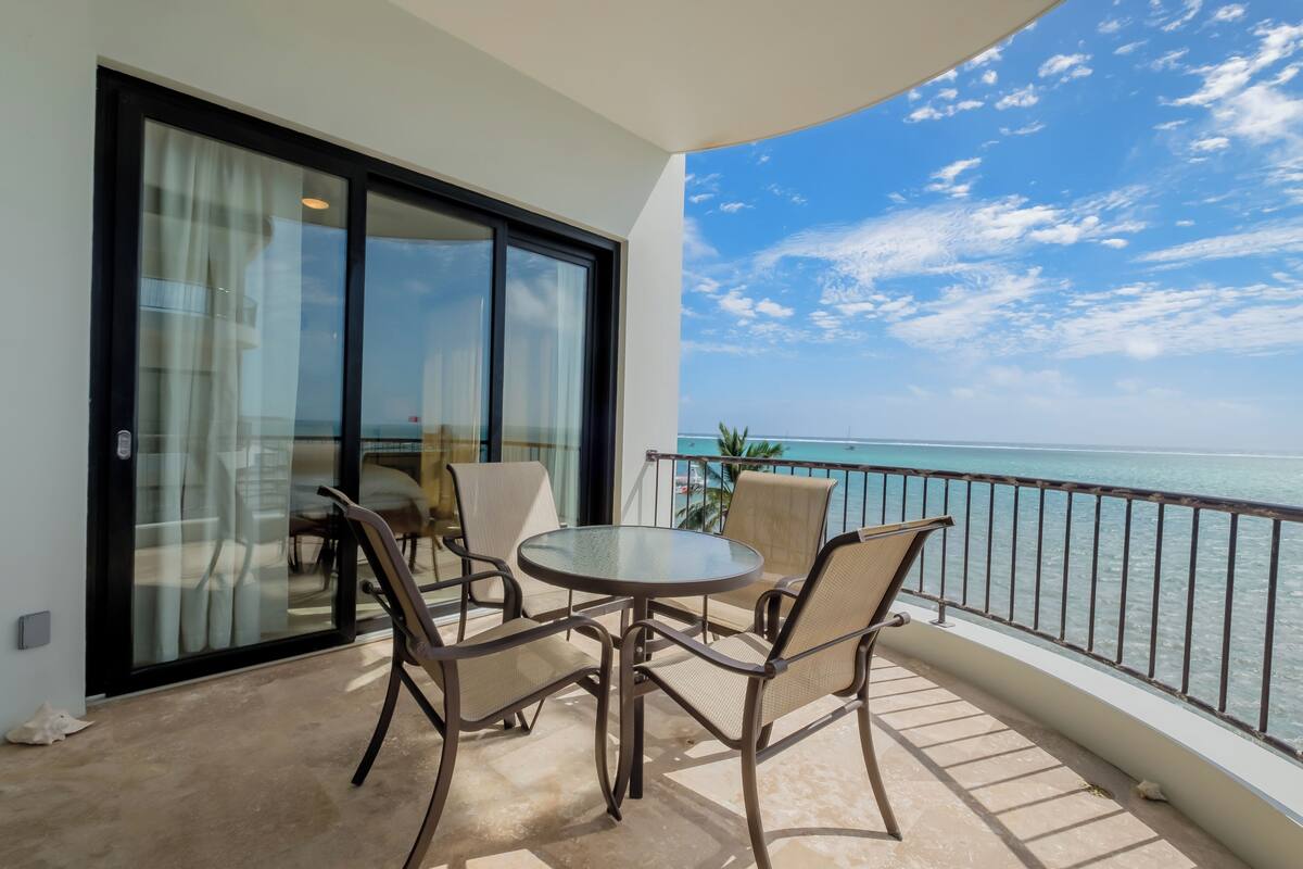 A balcony with a glass door, a round table, and four chairs.