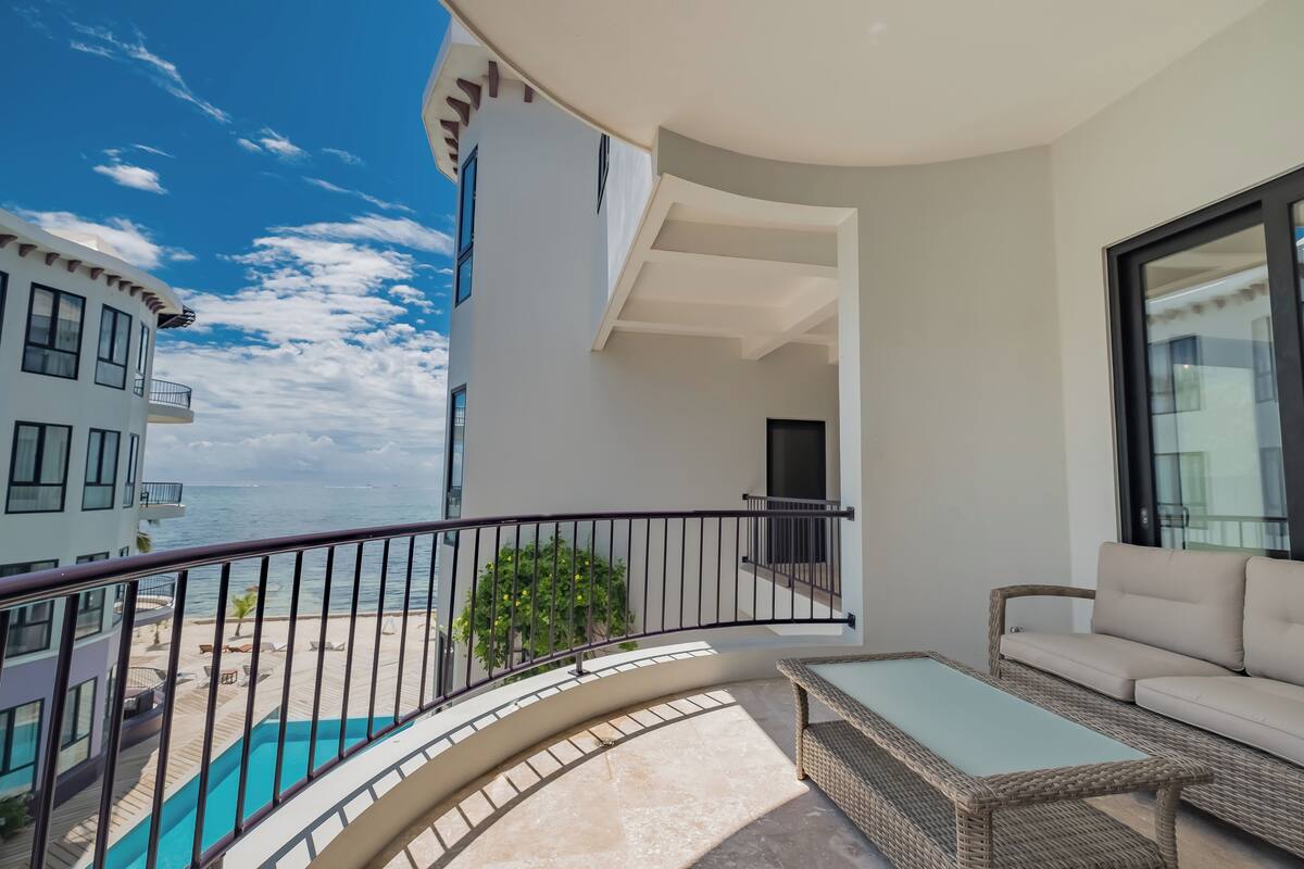 A balcony with a pool, a sofa, and a view of the ocean.