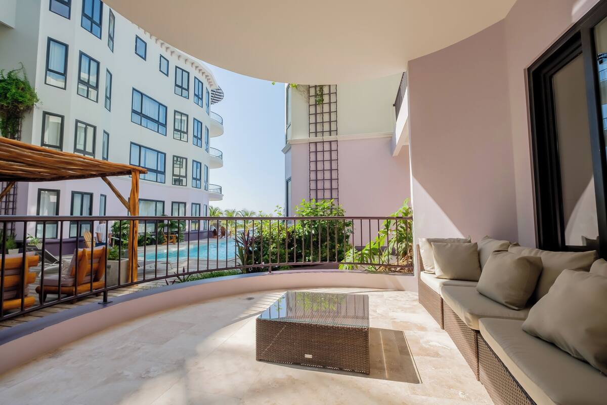 A balcony with a pool view, a sofa, and a table.