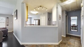 Een modern interieur met een grijze muur, een houten vloer en een keukenruimte zichtbaar door een open deur.