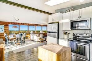 A modern kitchen with stainless steel appliances, a dining area with a view, and a cozy seating area.