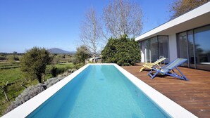 An infinity pool with a wooden deck, two lounge chairs, and a view of a mountainous landscape. - Villa 297 Charming Villa w/ Pool Near Moledo Beach (Moledo)