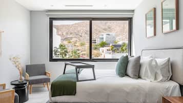 Une chambre moderne avec un grand lit, une vue sur un paysage montagneux et une fenêtre dotée d’un cadre noir.