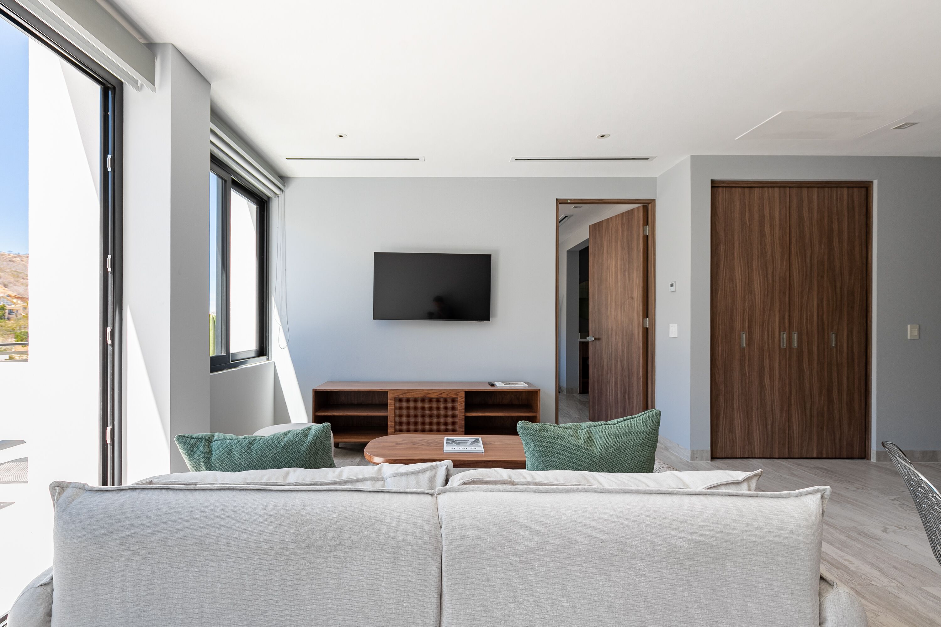 Una sala de estar moderna con un sofá, una mesa de centro y un televisor de pantalla plana montado en la pared.