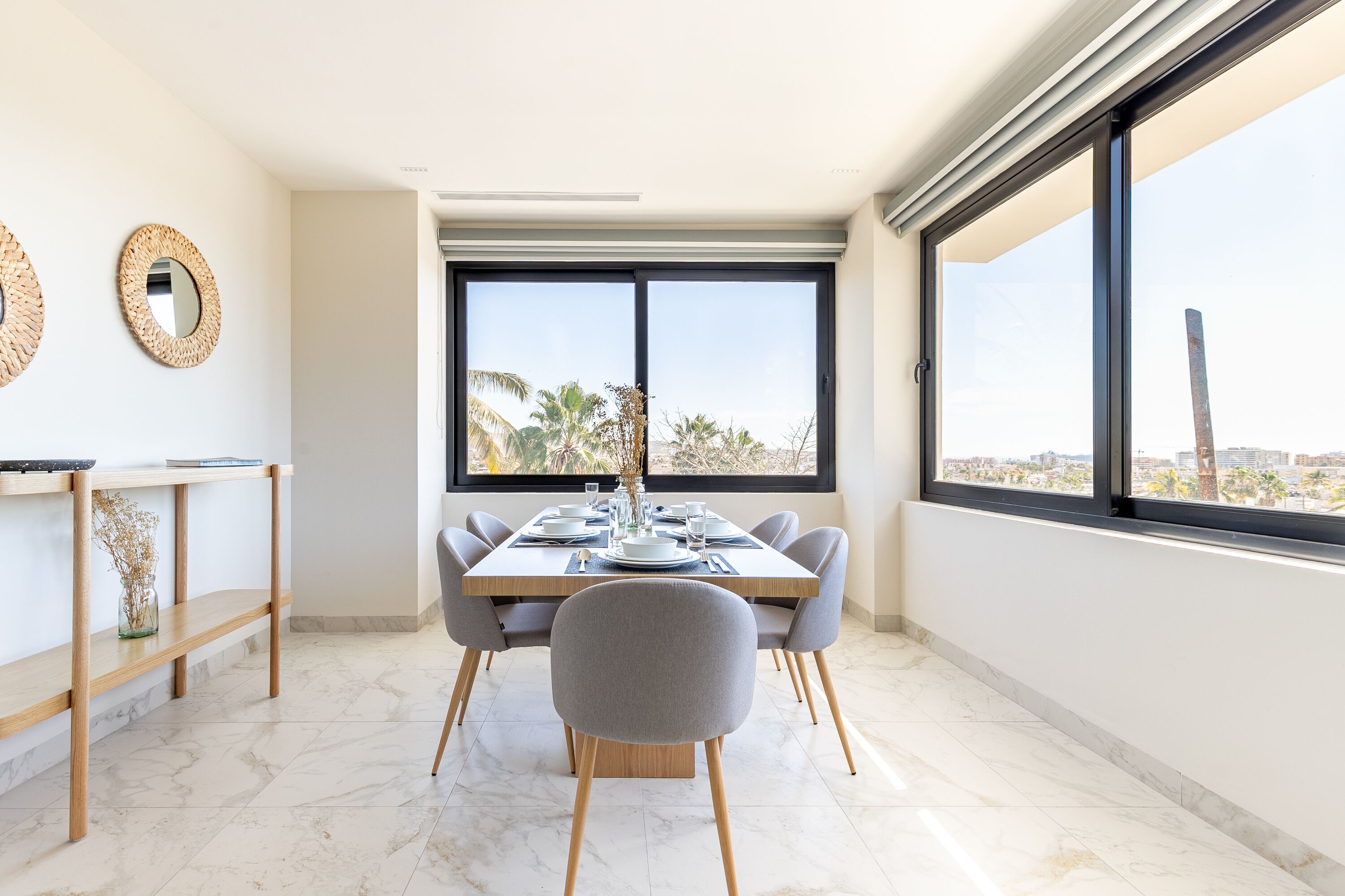 Un comedor moderno con una gran mesa preparada para seis comensales, una consola de madera y un amplio ventanal con vista a la ciudad.