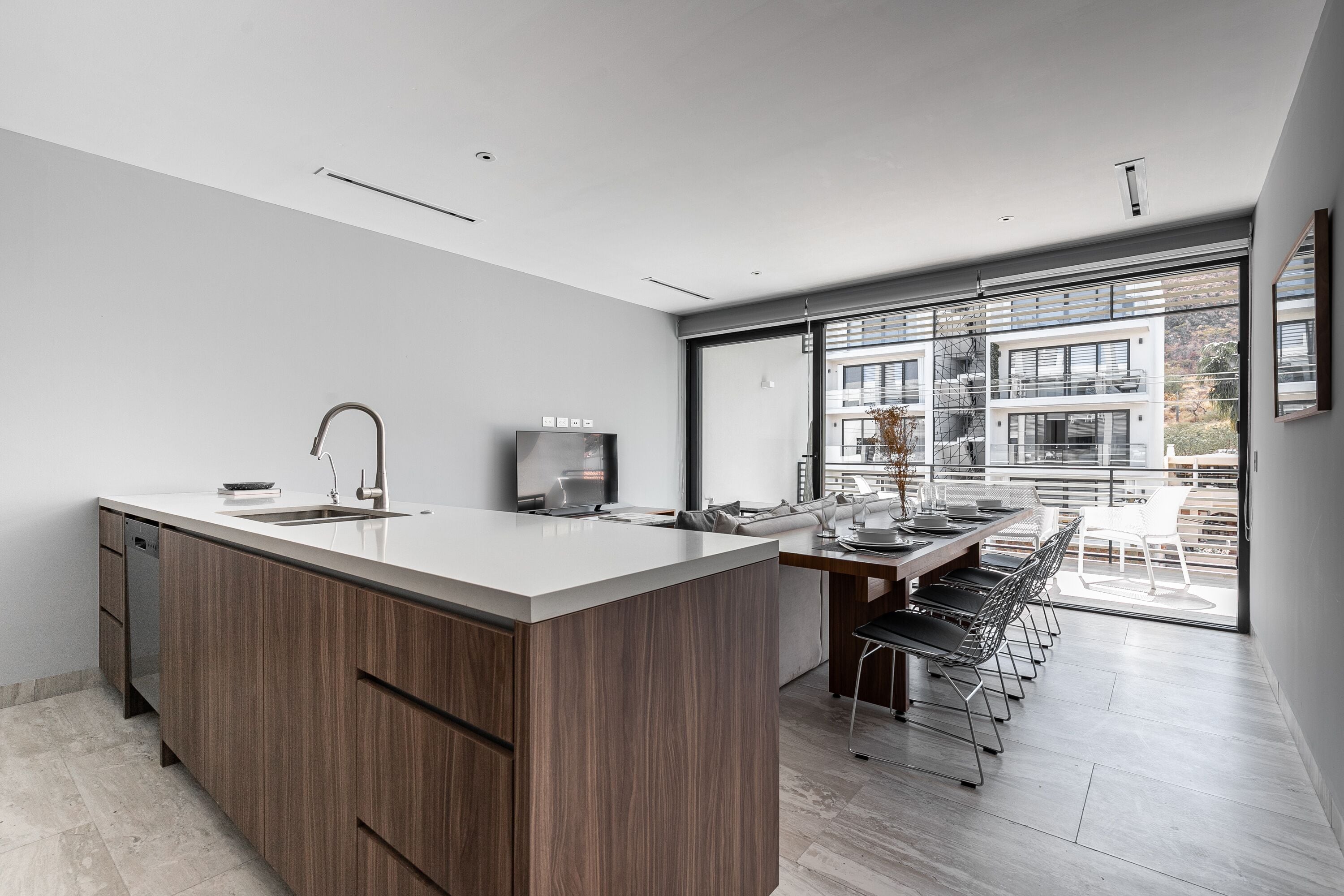 A modern kitchen with a large island, built-in appliances, and a dining area with a view to the outdoors.
