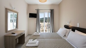 Ett hotellrum med en säng, ett skrivbord, en TV och en balkong med utsikt.