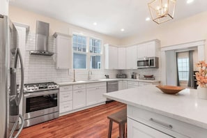 Una cocina moderna con armarios blancos, electrodomésticos de acero inoxidable y piso de madera.