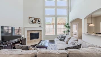 Un salon spacieux doté d’un grand téléviseur à écran plat, d’une cheminée et d’un canapé confortable.