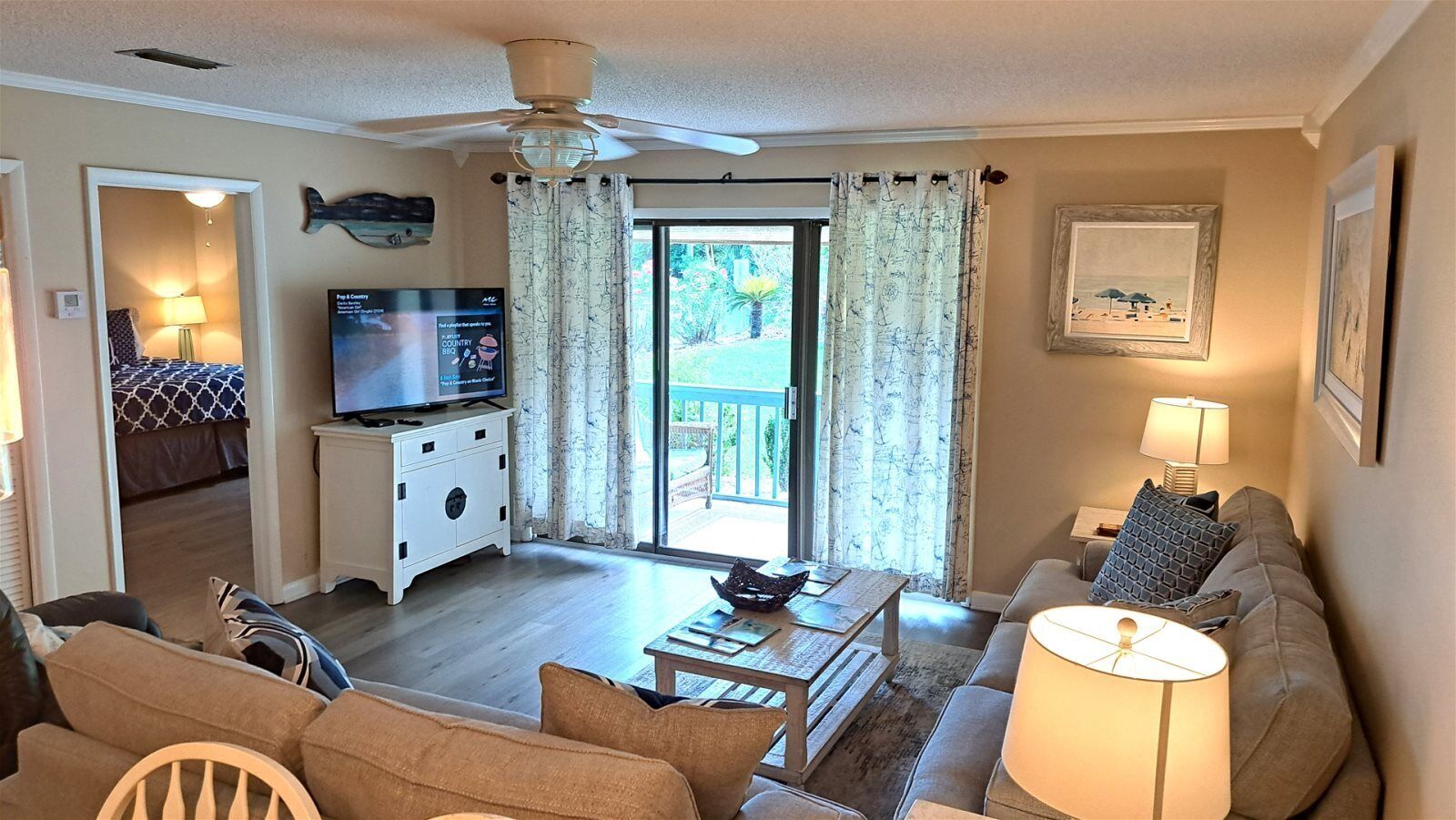 A living room with a television, a sofa, a coffee table, and a ceiling fan.