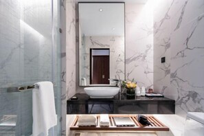 A modern bathroom with a large mirror, a white vessel sink, and a wooden vanity with towels. - Mandala Hotel Imperial Dragon Bay Debao (Debao)