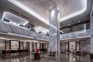 Eine großzügige Lobby mit Marmorboden, einer zentralen Säule und einer Sitzecke mit Sesseln.