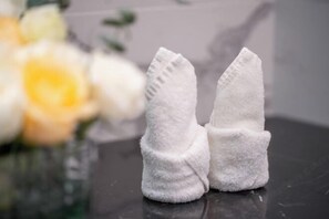 A pair of white towels on a reflective surface with a blurred yellow flower in the background. - Mandala Hotel Imperial Dragon Bay Debao (Debao)