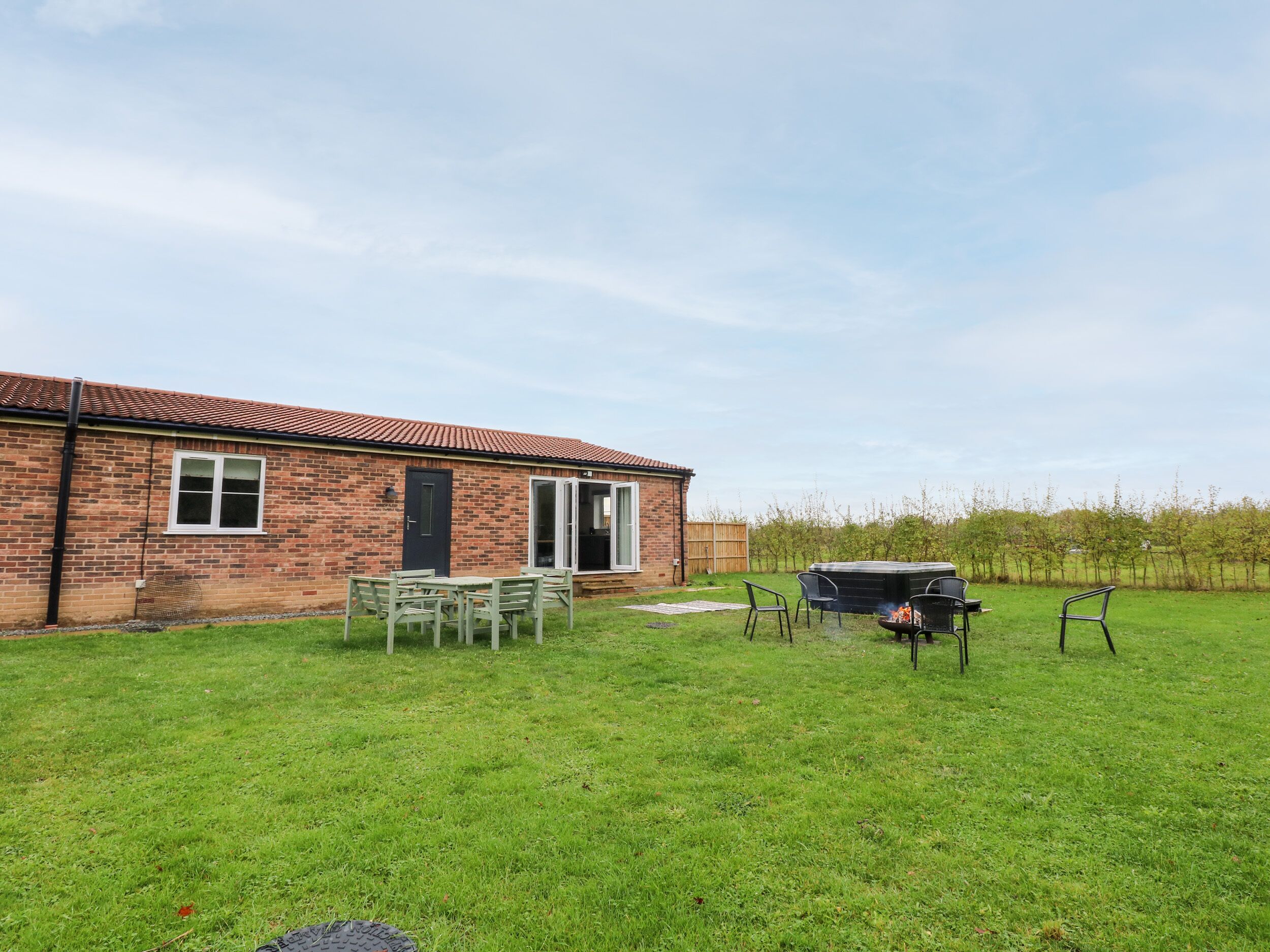 A brick house with a patio area, a barbecue grill, and a hot tub.
