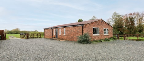 A brick building with a gravel driveway and wooden fences.