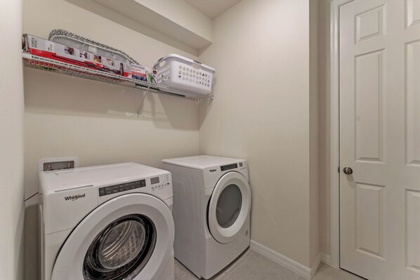 A laundry room with two Whirlpool washers, a shelf with laundry baskets, and a white door. - 9 Bedrooms/ 6.5 Bathrooms/ Solara Resort (8905 TH) (Kissimmee)