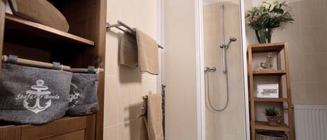 Un baño con tocador de madera, cabina de ducha de vidrio y repisa con adornos.