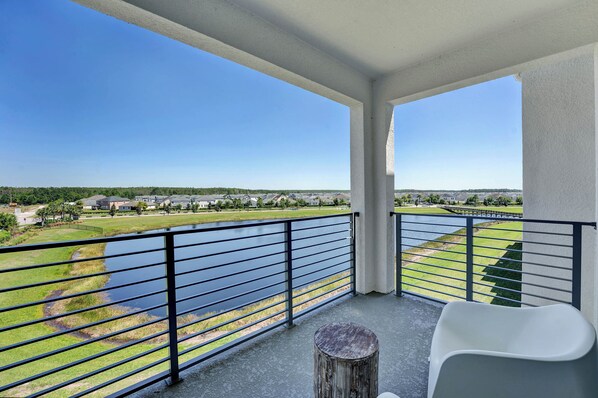 Un balcon avec vue sur un lac, une pelouse et un terrain de golf.
