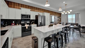A modern kitchen with white cabinets, a central island, and a dining area with a table and chairs. - 2 Bedrooms/ 2 Bathrooms/ Storey Lake (3191-405 PC) (Kissimmee)