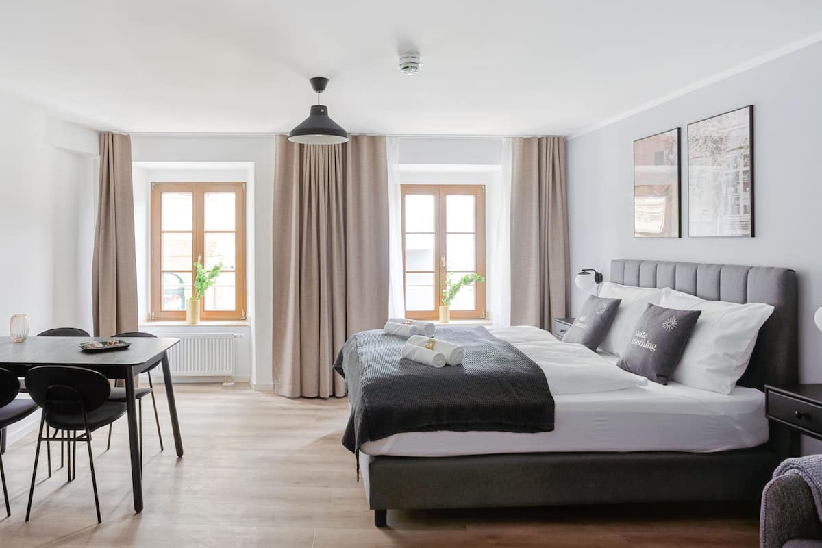 Une chambre moderne avec un lit, un bureau et deux fenêtres équipées de rideaux.