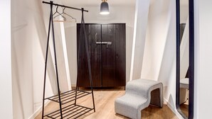 Une chambre moderne avec un plancher en bois, une balançoire en métal noir, un banc gris, une armoire et un grand miroir.