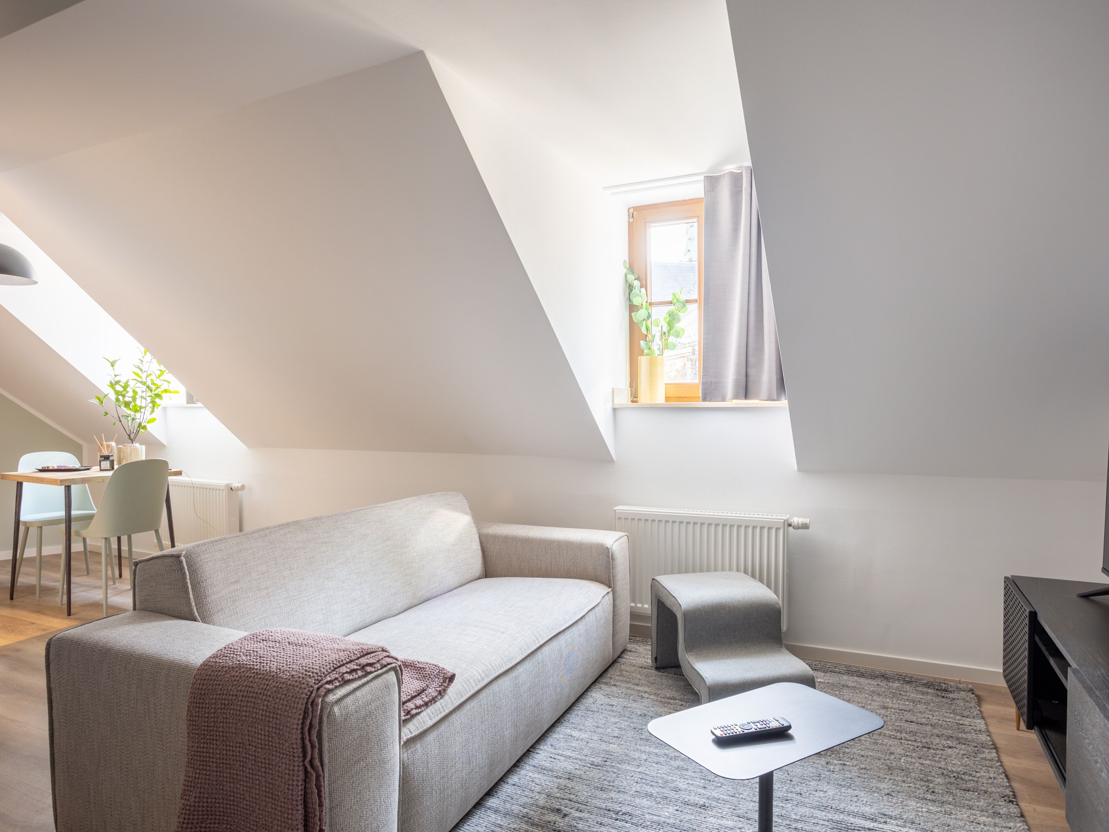 A modern loft-style living room with a high ceiling, a sofa, a coffee table, and a television.