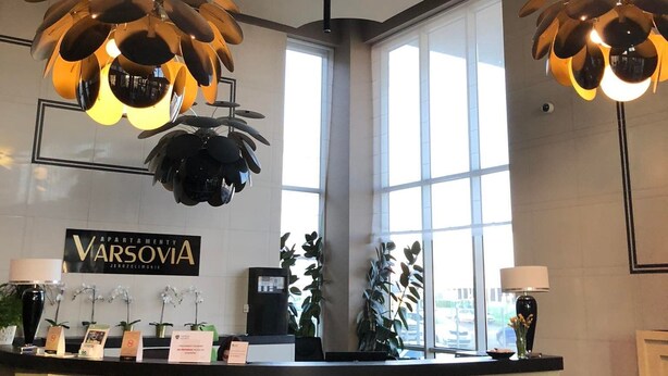 A reception desk with a modern design, large windows, and a sign reading "Varsovia". - Apartamenty Varsovia 304 (Warsaw)